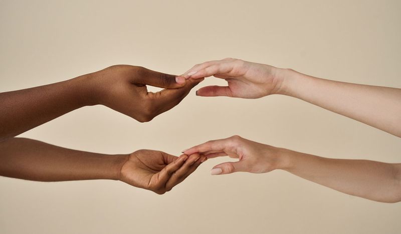 Twee westerse en afrikaanse handen raken elkaar aan als handmodel van Shootz