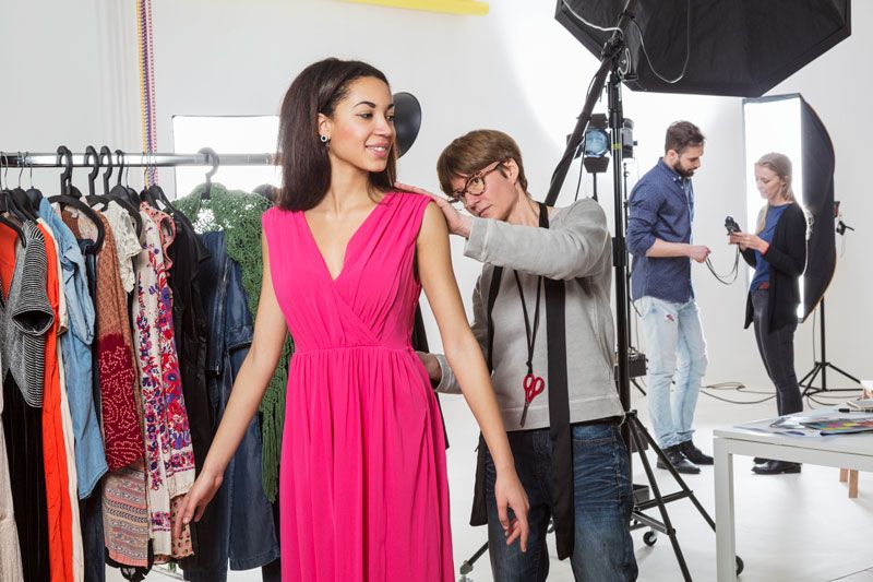 Kledingstylist werkt kleding bij van een model van Shootz op de set. 