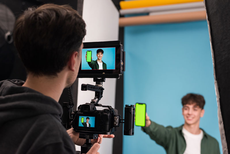 Acteur van Shootz toont telefoon met video aan cameraman die hem filmt.