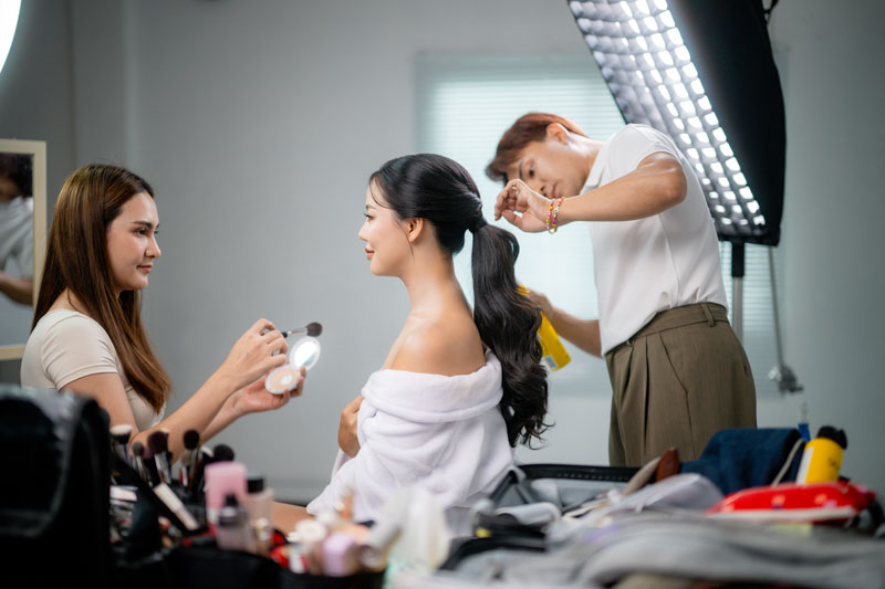 Visagist en haarstylist maken een model van Shootz klaar voor een fotoshoot